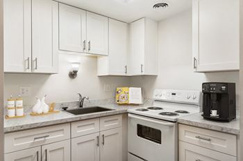 A kitchen with white cabinets and white appliances and a sink
